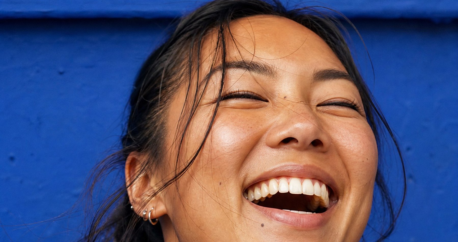 Woman laughing against a blue wall