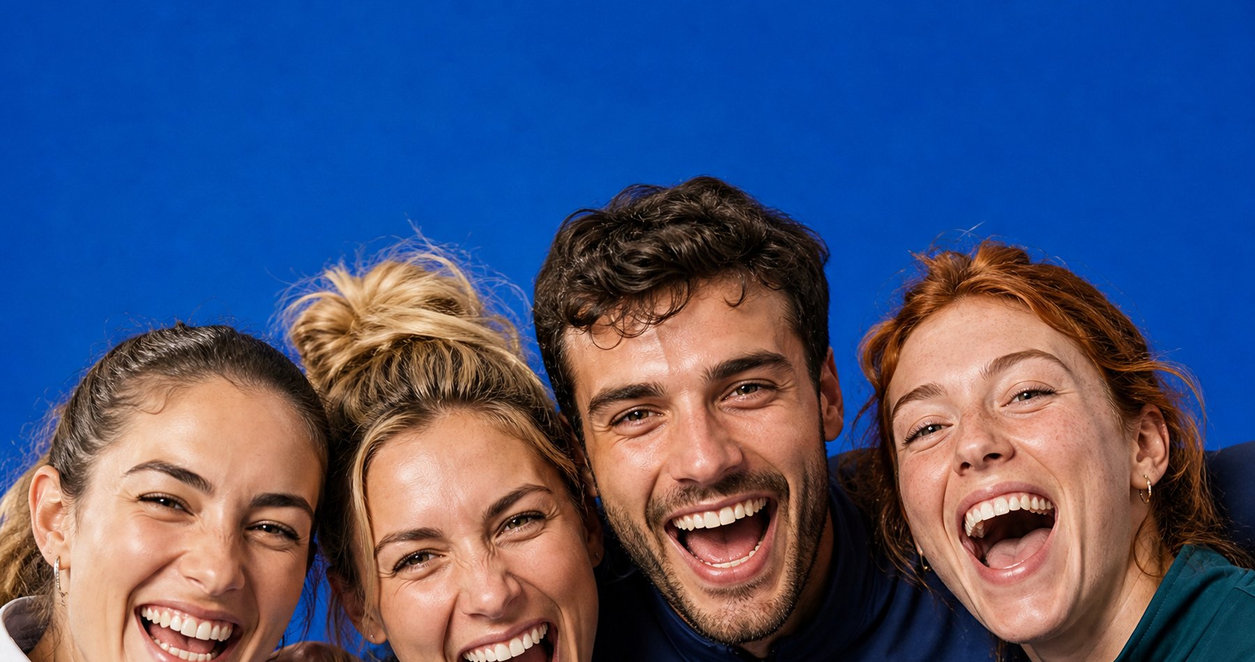 Four friends cheering against a blue wall