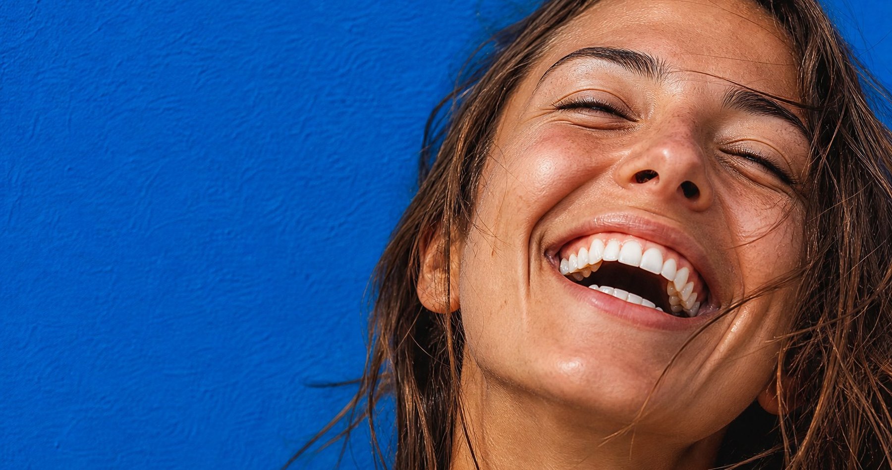 Woman laughing against a blue wall